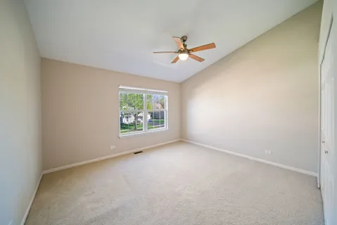 an empty room with windows and ceiling fan