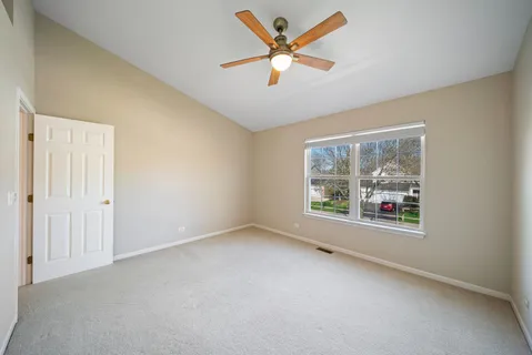 an empty room with windows and ceiling fan