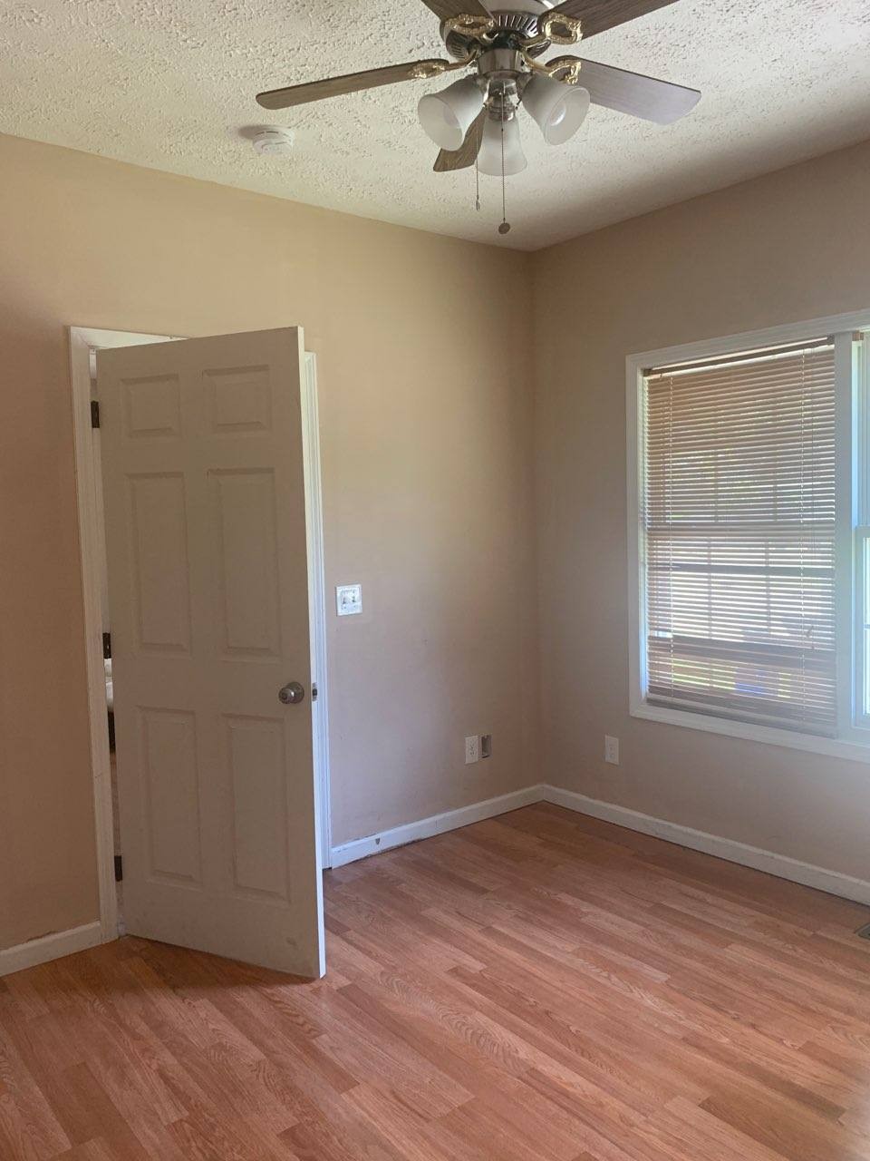 605 South Spring Street Manchester, TN 37355 - Photo 6 of 6 an empty room with wooden floor chandelier fan and windows