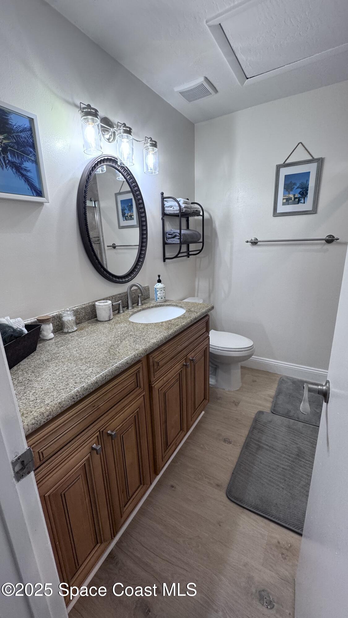 1841 Island Club Drive, Unit 472 Indialantic, FL 32903 - Photo 17 of 23 a bathroom with a granite countertop toilet a sink and a mirror