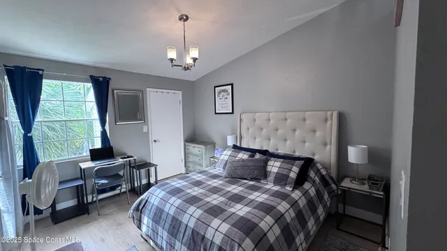 a bedroom with a bed a chandelier and a window