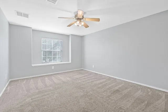 an empty room with windows and ceiling fan