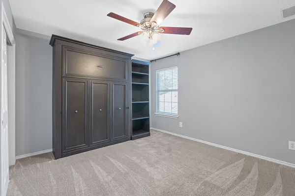 an empty room with windows and fan