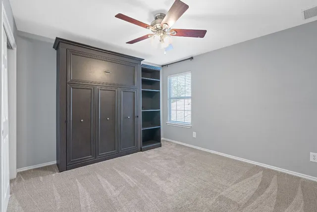 an empty room with windows and fan