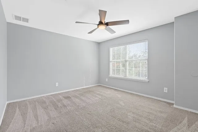 an empty room with windows and fan