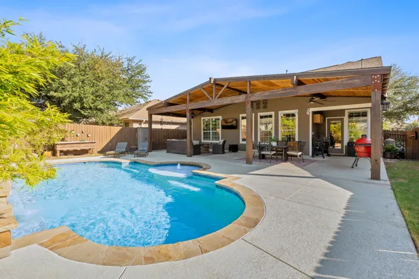 a view of a house with pool chairs and a yard