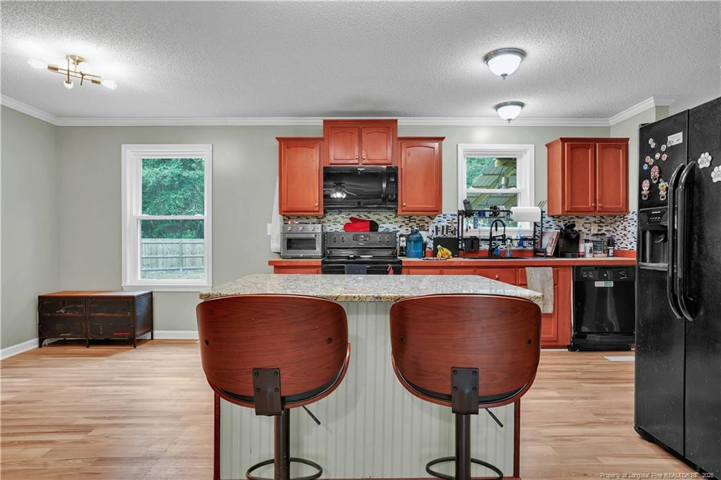 8155 Arabia Road Lumber Bridge, NC 28357 - Photo 7 of 30 a kitchen with stainless steel appliances granite countertop a refrigerator a stove a sink dishwasher with a dining table and chair with wooden floor