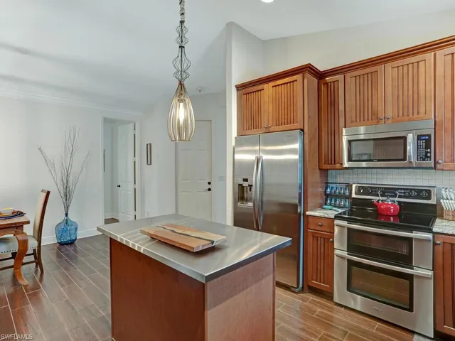 a kitchen with stainless steel appliances granite countertop a refrigerator a stove and a wooden floors
