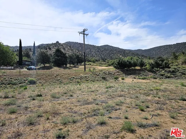 a view of a dry field with mountains in the background