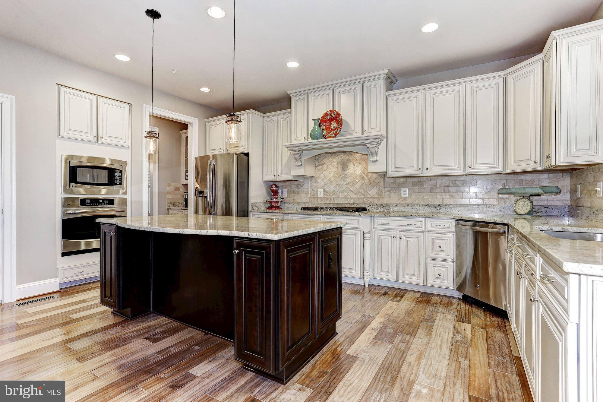 7806 Blue Ribbon Street Fulton, MD 20759 - Photo 6 of 30 a kitchen with kitchen island granite countertop a wooden cabinets and white appliances