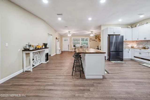 a large white kitchen with wooden floor and a sink
