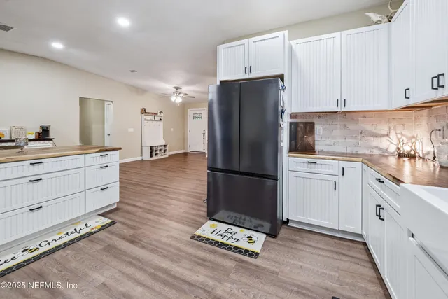 a kitchen with a sink dishwasher stove and white cabinets with wooden floor