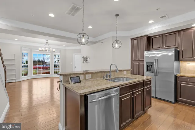 a kitchen with kitchen island granite countertop a refrigerator a sink and wooden floor