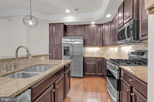 a kitchen with stainless steel appliances granite countertop a sink a stove and a refrigerator