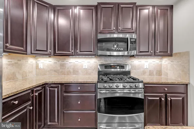 a kitchen with granite countertop wooden cabinets and stainless steel appliances