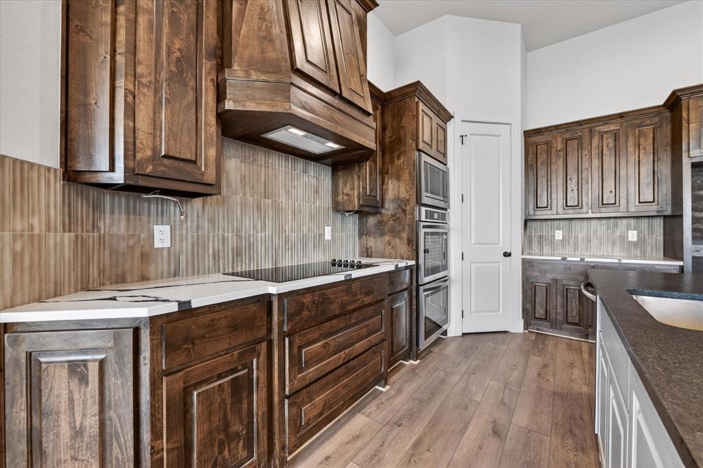 517 Longhorn Lane Springtown, TX 76082 - Photo 12 of 39 Kitchen with backsplash, light wood-style floors, dark wood finish cabinetry, and stainless steel appliances