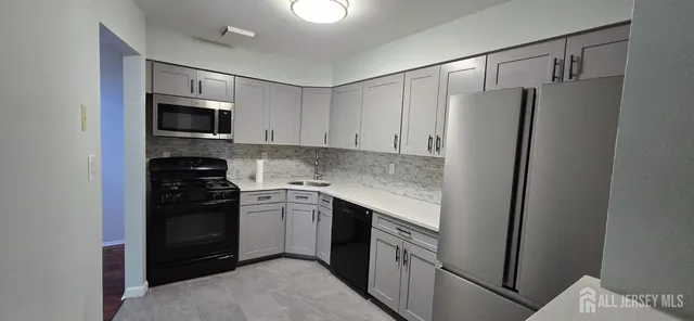 a kitchen with stainless steel appliances granite countertop white cabinets a refrigerator and a stove