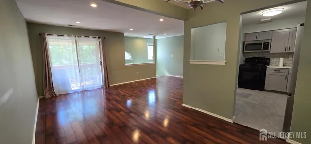 a view of a hallway with wooden floor and a kitchen