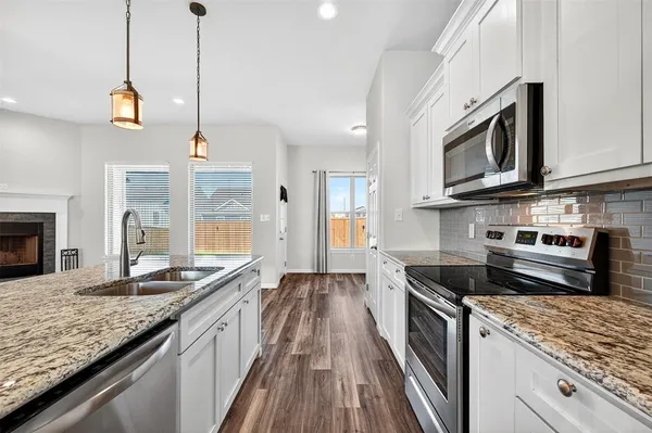 a kitchen with stainless steel appliances granite countertop a stove a sink and a microwave