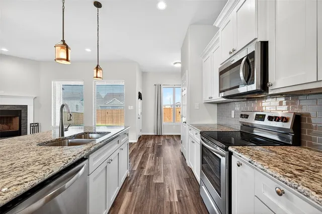 a kitchen with stainless steel appliances granite countertop a stove a sink and a microwave