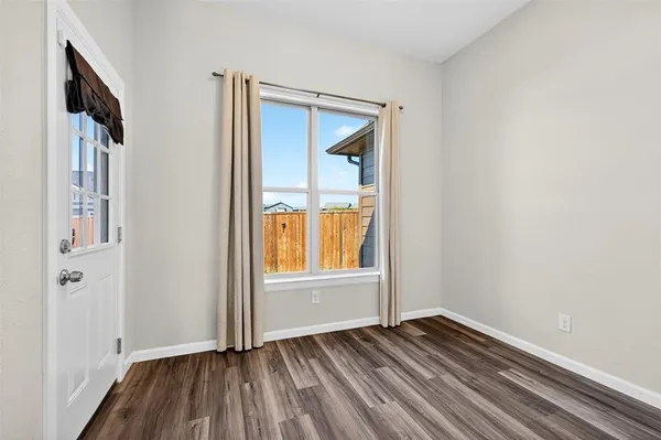 a view of an empty room with wooden floor and a window