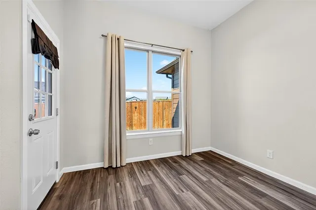 a view of an empty room with wooden floor and a window