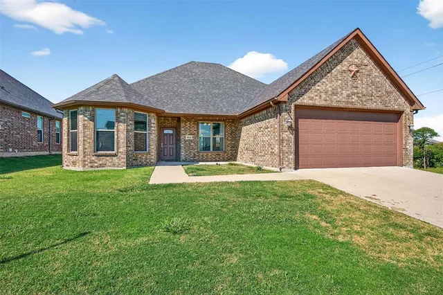 a view of a house with a yard potted plants and a large tree