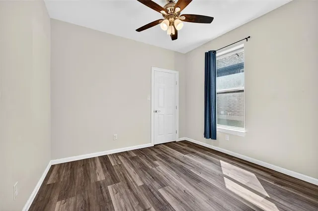 an empty room with wooden floor fan and windows