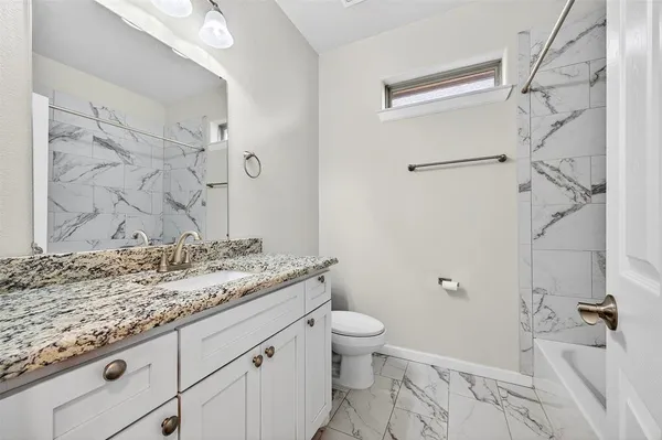 a bathroom with a granite countertop sink toilet and shower