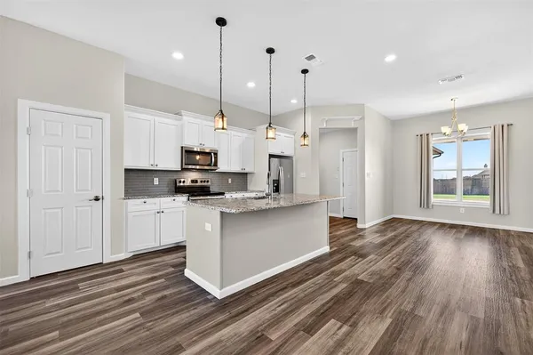 a kitchen with stainless steel appliances granite countertop a refrigerator a stove and a wooden floors