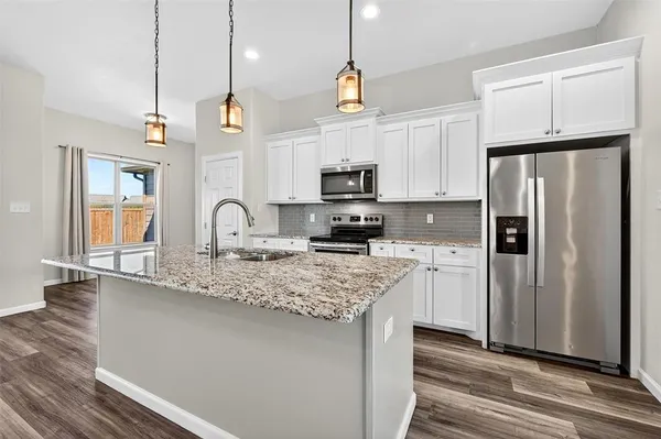 a kitchen with stainless steel appliances granite countertop a sink a refrigerator a stove a microwave and wooden floor