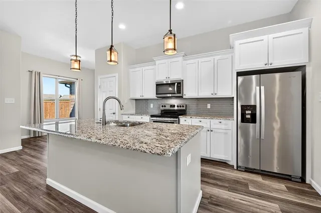 a kitchen with stainless steel appliances granite countertop a sink a refrigerator a stove a microwave and wooden floor