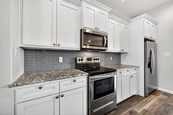 a kitchen with granite countertop white cabinets and stainless steel appliances
