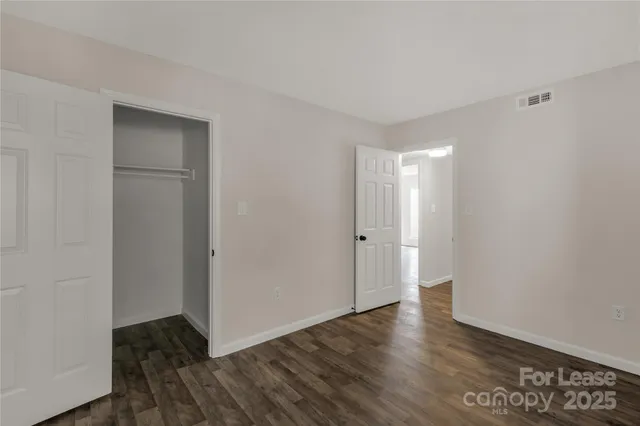 a view of an empty room with wooden floor and closet