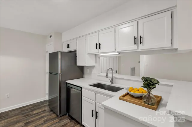 a kitchen with stainless steel appliances granite countertop a sink a refrigerator a stove and white cabinets