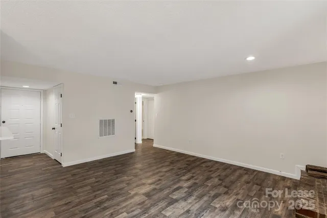 a view of an empty room with wooden floor and closet