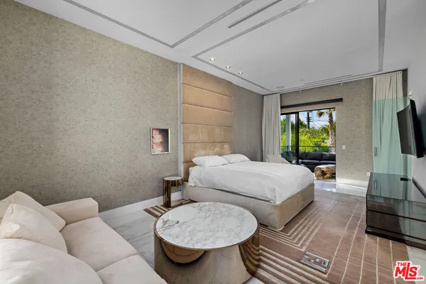 a bedroom with a bed a couch and a flat screen tv