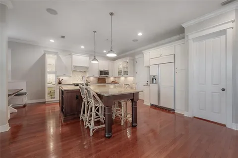 a kitchen with stainless steel appliances a dining table chairs stove refrigerator and cabinets