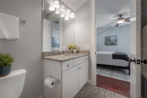 a en suite bathroom with a granite countertop sink a toilet and a mirror
