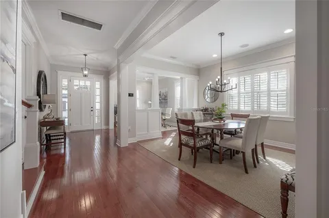 a view of a dining room and livingroom with furniture wooden floor a chandelier
