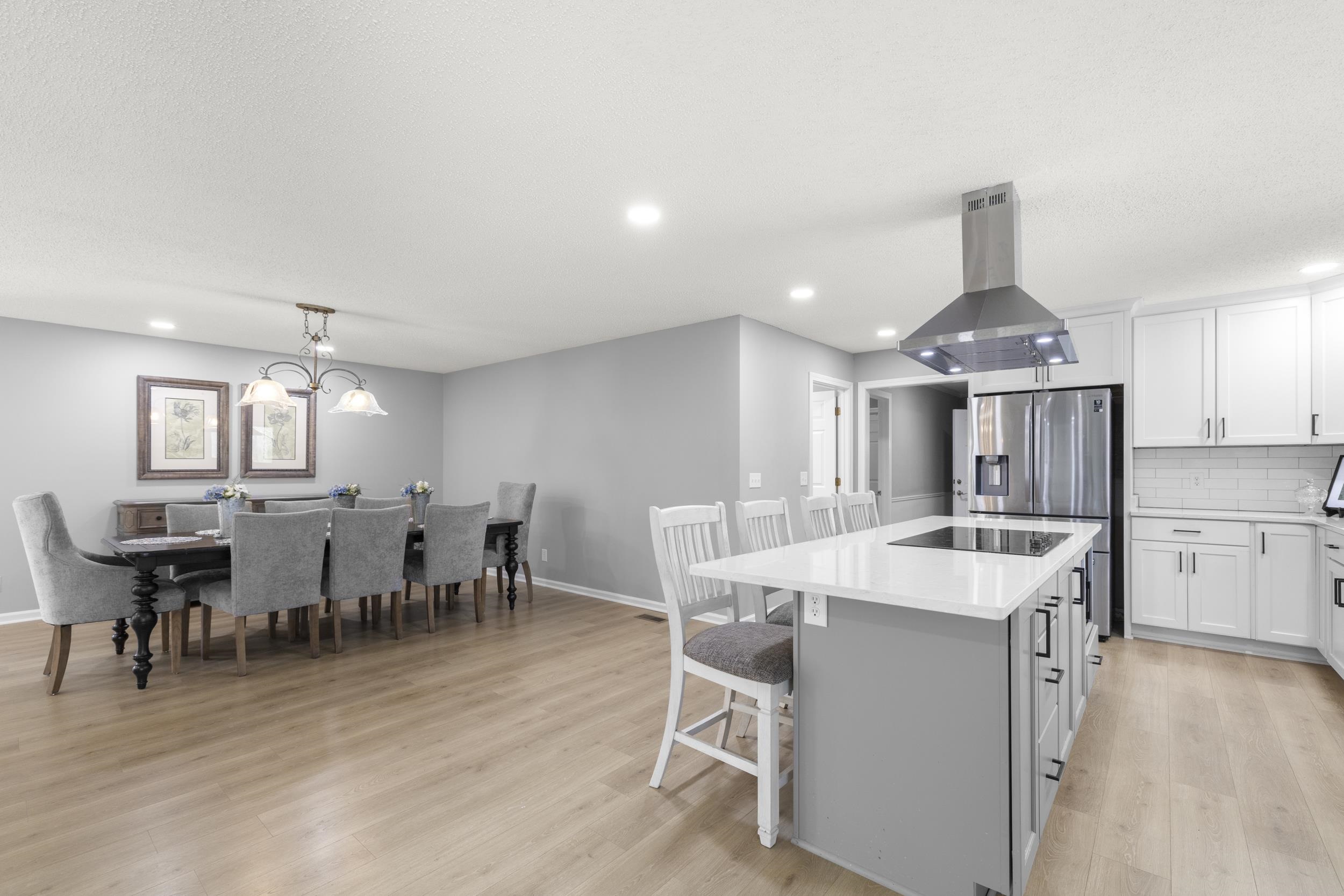 460 Woodbridge Road Somerville, TN 38068 - Photo 11 of 40 Dual tone kitchen featuring a kitchen island, island exhaust hood, backsplash, a breakfast bar, and light wood-style flooring