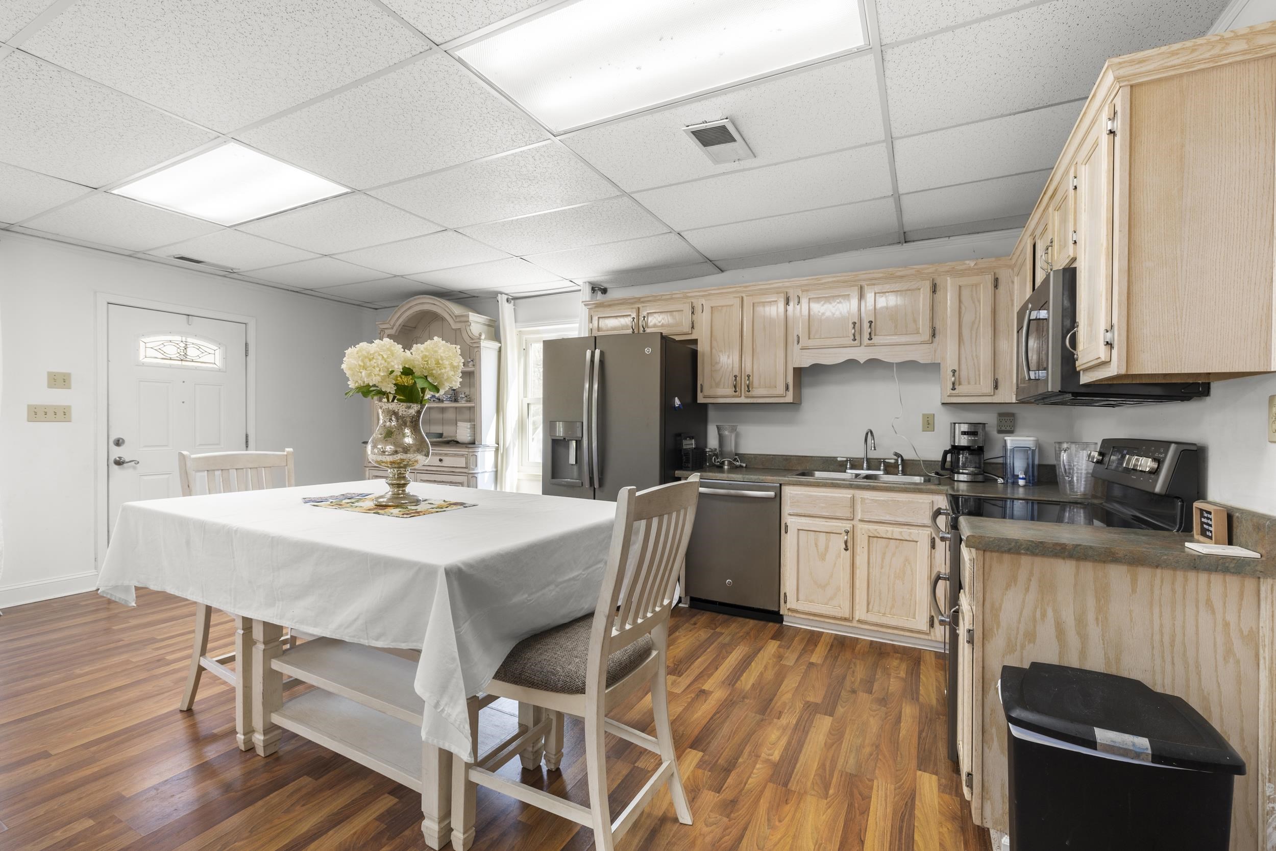 460 Woodbridge Road Somerville, TN 38068 - Photo 35 of 40 Kitchen with dark countertops, light wood finish cabinets, stainless steel appliances, a paneled ceiling, and dark wood finished floors