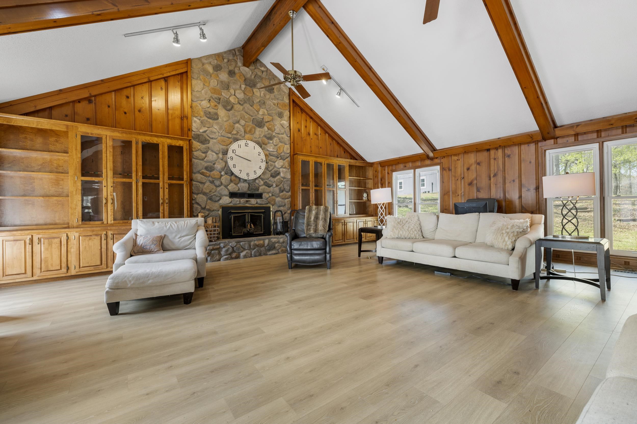 460 Woodbridge Road Somerville, TN 38068 - Photo 9 of 40 Family Room featuring wooden walls, rail lighting, a stone fireplace, light wood finished floors, and plenty of natural light