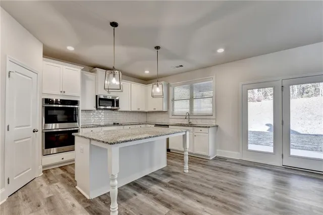 a kitchen with kitchen island granite countertop a sink cabinets stainless steel appliances and a counter space