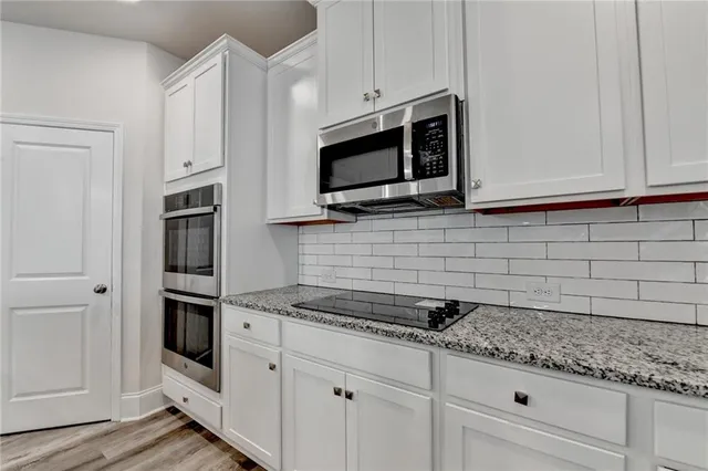 a kitchen with stainless steel appliances granite countertop a sink a stove and cabinets