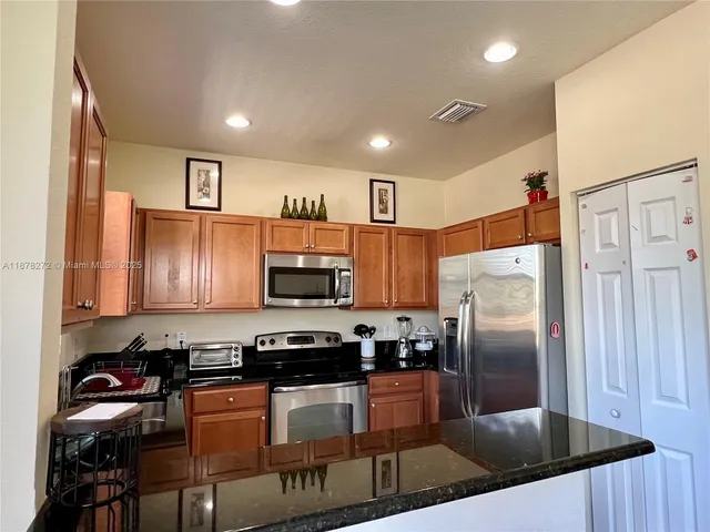 a kitchen with stainless steel appliances granite countertop a refrigerator a stove a sink and a microwave