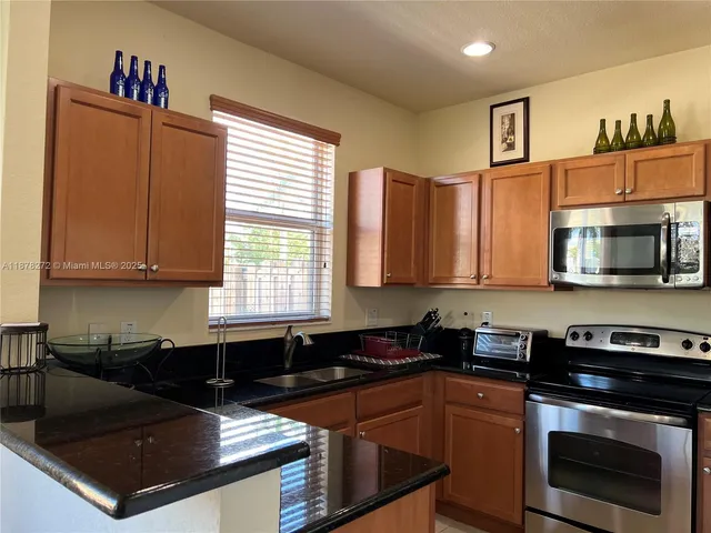 a kitchen with stainless steel appliances granite countertop a stove a sink and a microwave