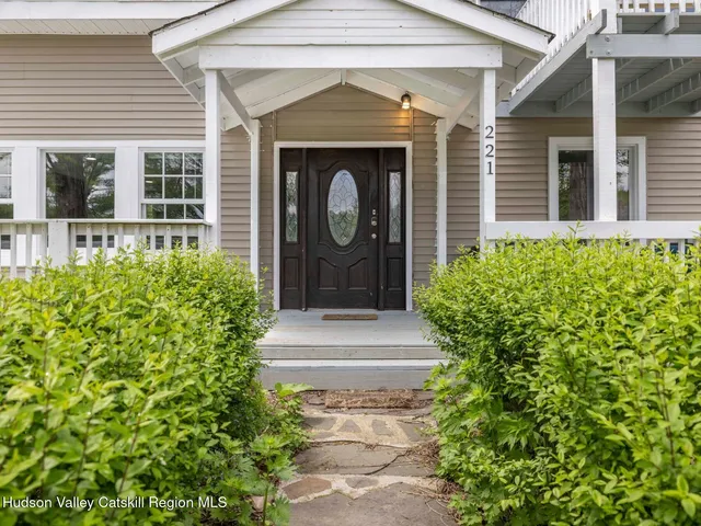 a view of a yard in front of a house with plants and large trees