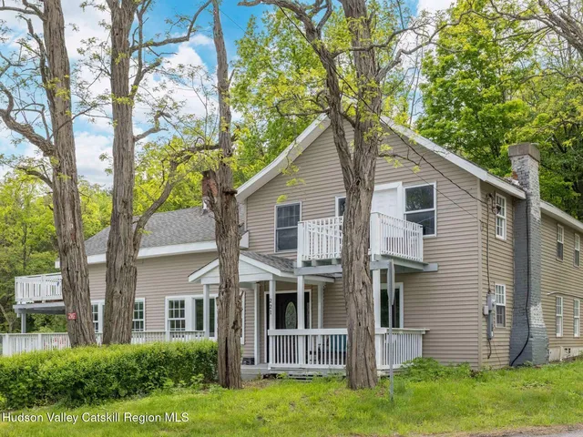 a view of a house with a big yard and large trees
