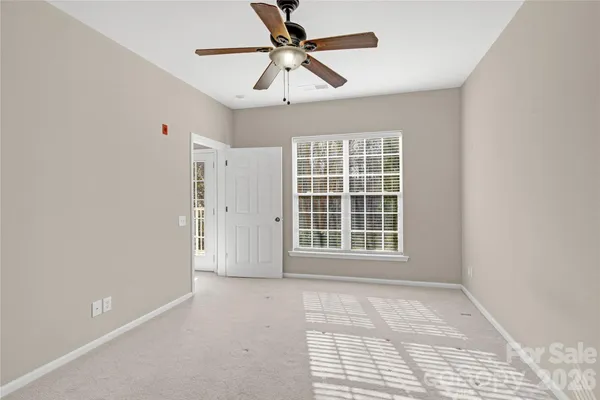 an empty room with windows and ceiling fan